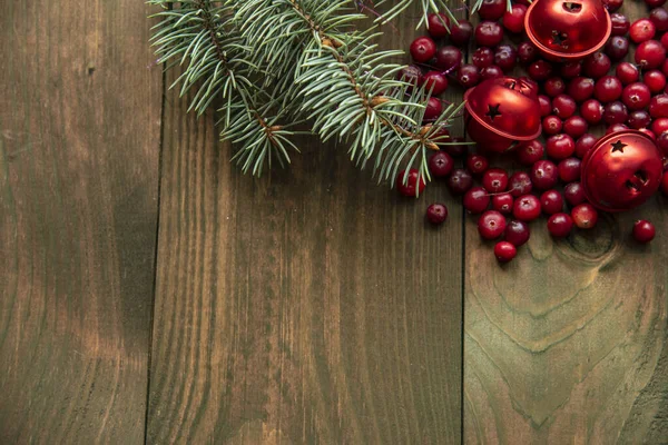 Rama de abeto azul, arándanos y campanas rojas de Navidad sobre un fondo de madera . — Foto de Stock