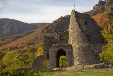 Yıkılmış tuğla kule, duvar ve kapı dağların ve gökyüzünün arka planına karşı..