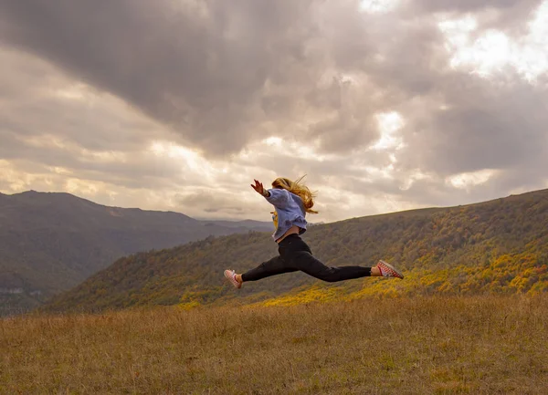 Menina pulando no fundo das montanhas de outono e céu . — Fotografia de Stock