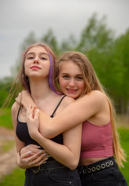 Duas meninas adolescentes com cabelos longos em uma caminhada abraçam um ao outro . — Fotografia de Stock