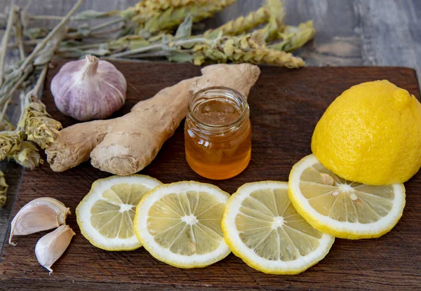 Gingembre, citron, ail et thé de Mursal de montagne sur une planche de bois rugueuse . — Photo