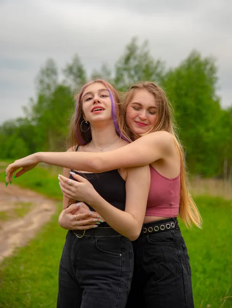 Две девочки-подростки с длинными волосами на прогулке обнимают друг друга . — стоковое фото