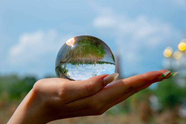 The glass ball lies in the woman's palm. The ball reflects the monastery and nature.