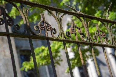 Bulanık bir arkaplanda zamanla paslanmış metal bir çit parçası..