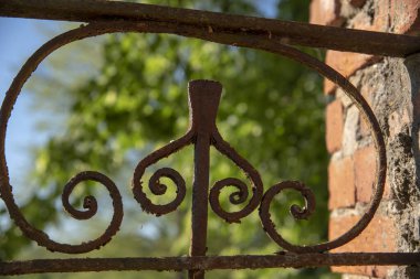 Bulanık bir arkaplanda zamanla paslanmış metal bir çit parçası..