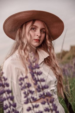 Şapkalı ve beyaz gömlekli çekici sarışın bir kızın büyük portresi. .