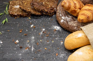 Koyu arkaplanda farklı ekmek ve beyaz undan yapılmış çerçeve. Fırın ürünleri için metin, tasarım ve reklam alanı kopyala.