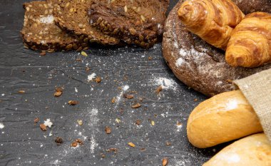Koyu arkaplanda farklı ekmek ve beyaz undan yapılmış çerçeve. Fırın ürünleri için metin, tasarım ve reklam alanı kopyala.