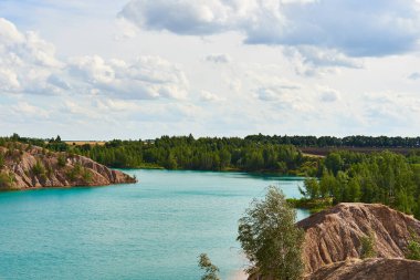 Parlak yaz manzarası. Mavi göl kumlu tepelerin arasında bulutlu gökyüzünün dokulu arka planında.