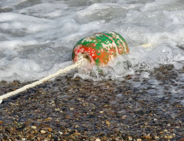 Une vieille bouée battue dans les vagues de la mer. — Photo