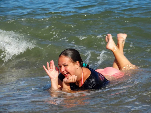 Una adolescente riendo yace en las olas del mar. —  Fotos de Stock