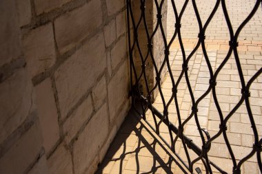 Metal ızgaranın soyut bir deseni, gölgesi fayansların üzerine düşüyor. .