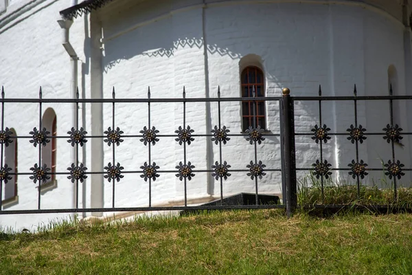 阳光灿烂的日子里 修道院白色砖墙上的金属栅栏 — 图库照片
