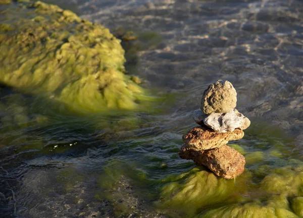Batu Batu Bertekstur Ditumpuk Piramida Dengan Latar Belakang Air Laut — Stok Foto