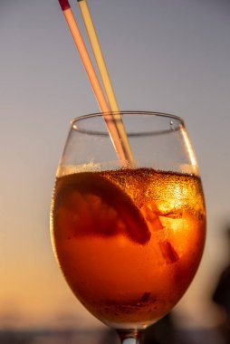 Bir bardak aperol kokteyli bir plaj kafesinde gün batımına karşı durur..