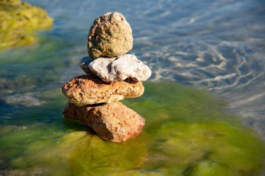 Saf deniz suyunun arka planına karşı bir piramide istiflenmiş desenli taşlar. Metin ve tasarım için boşluk kopyala.