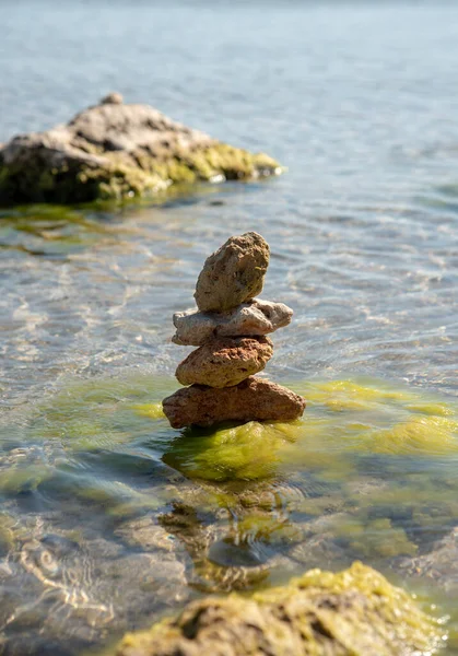 Saf deniz suyunun arka planına karşı bir piramide istiflenmiş desenli taşlar. Metin ve tasarım için boşluk kopyala.