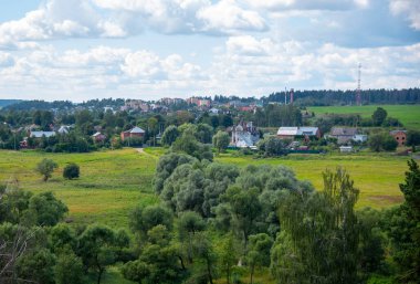 Yaz manzarası. Tepeden tarlalara, ormandan köye bulutlu bir gökyüzünün altında.