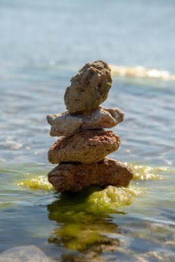 Saf deniz suyunun arka planına karşı bir piramide istiflenmiş desenli taşlar. Metin ve tasarım için boşluk kopyala.