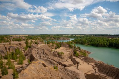 Parlak yaz manzarası. Kum tepelerinin arasında yeşil göl Bulutlu gökyüzünün dokulu arka planında.