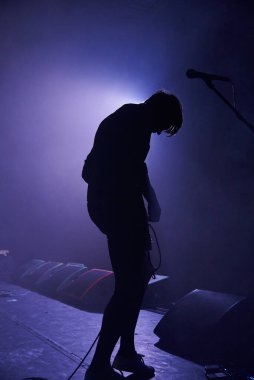 Hafif bulanık bir siluet dumandaki gitarlı genç bir adam, bir kontür ışıkla aydınlatılmış..