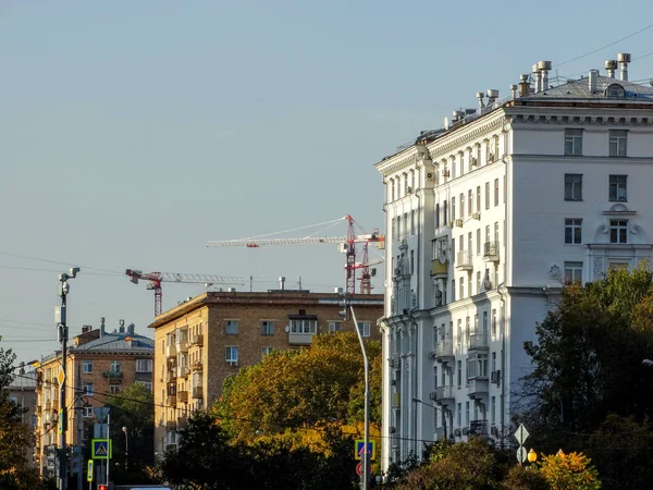 Fragment ulicy miejskiej z domami, dźwigami budowlanymi i przewodami elektrycznymi. — Zdjęcie stockowe