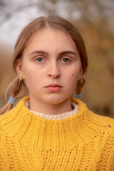 顔ポートレートのブロンド女の子で明るい暖かい黄色のセーター上の黒っぽいです背景の自然 — ストック写真