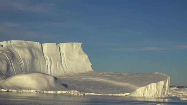 Antarktida. Krásný modrý ledovec se zrcadlovým odrazem se vznáší v otevřeném oceánu. Obloha zapadajícího slunce v pozadí. Majestátní zimní krajina. Cestování — Stock video