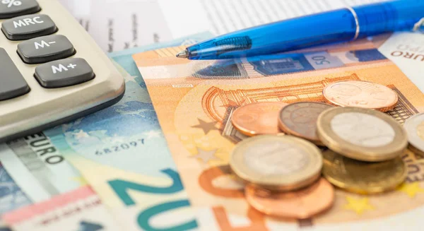 Een rekenmachine met euro-biljetten en euromunten — Stockfoto