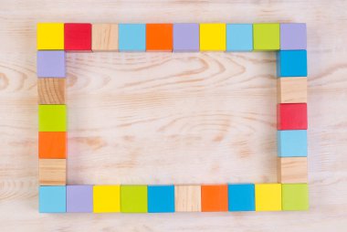 Beyaz ahşap zemin üzerinde renkli tahta bloklar çerçeve, kopyalama alanı ile üst görünüm