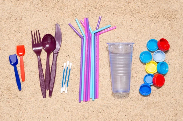 ボトル カップ フォーク スプーン 飲料用のストローなど 環境汚染の原因となるプラスチック製のオブジェクト 特に海洋を使い捨て可能です 砂の上からの眺め — ストック写真