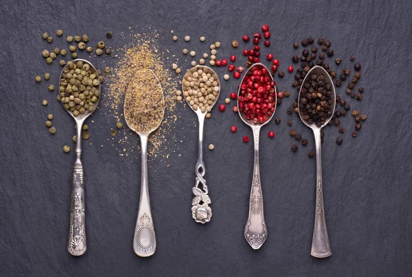 Various Kinds Peppercorns Silver Spoons Black Stone Background — Stock Photo, Image