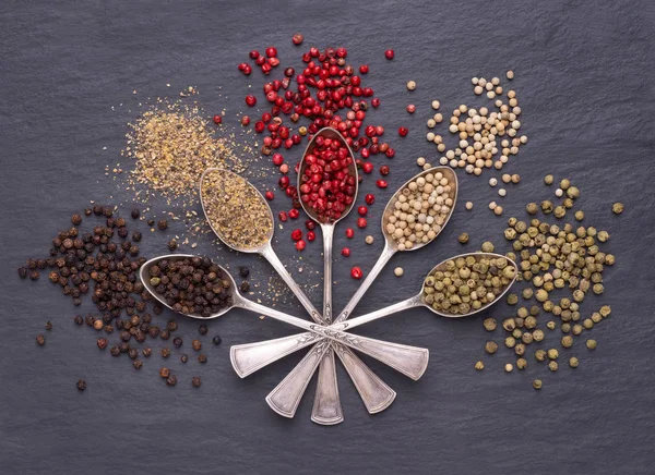 Various Kinds Peppercorns Silver Spoons Black Stone Background — 스톡 사진
