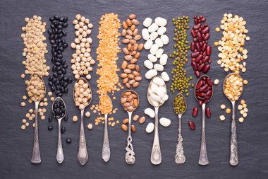 Legumes, mercimek, nohut, kuru bezelye ve arkaplanda kaşık içinde fasulye. Üst görünüm