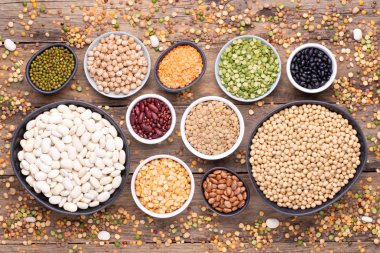 Legumes, mercimek, nohut ve fasulye çeşitleri çeşitli kaselerde ahşap arka plan, üst görünüm