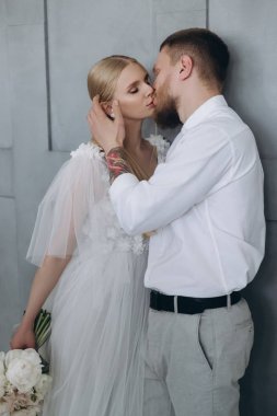 şık genç gelin ve damat öpüşme gri duvarın önünde