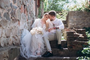 bride and groom sitting on stairs at old town clipart