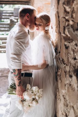 attractive young cuddling bride and groom inside of ancient building clipart