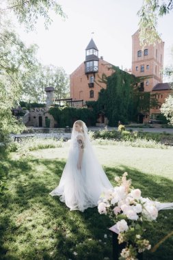 beautiful young bride in garden in front of ancient castle clipart