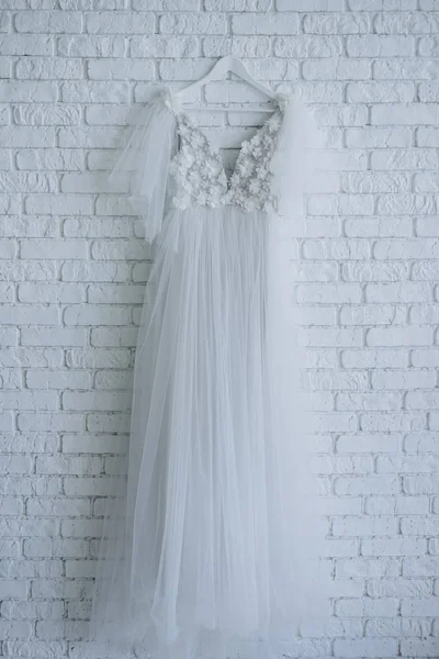 Красивое Свадебное Платье Украшено Цветами Висящими Белой Кирпичной Стене — стоковое фото