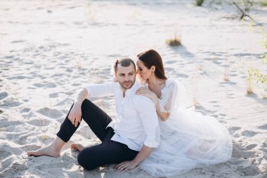 güzel genç aile kucaklayan ve kumsalda oturuyor