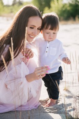 gülümseyen anne ile küçük oğlu kum plajındaki vakit