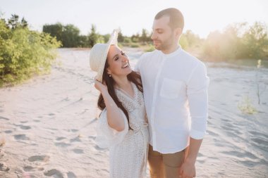Sahilde yakışıklı adamla şapka sarılma içinde güzel gülen kadın