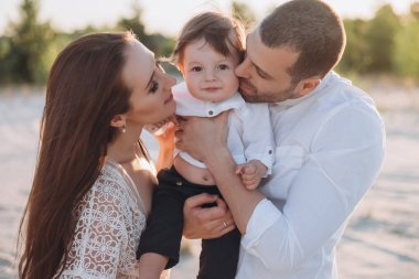 mutlu anne ve baba küçük oğlu kumsalda sarılma