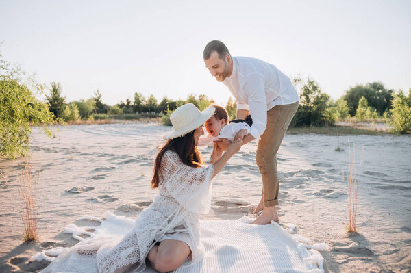 счастливые родители играют с маленьким сыном на пляже
