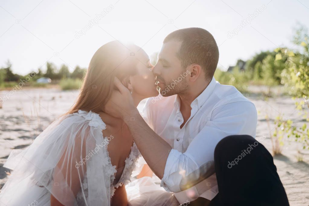 beautiful happy couple kissing on beach with back light