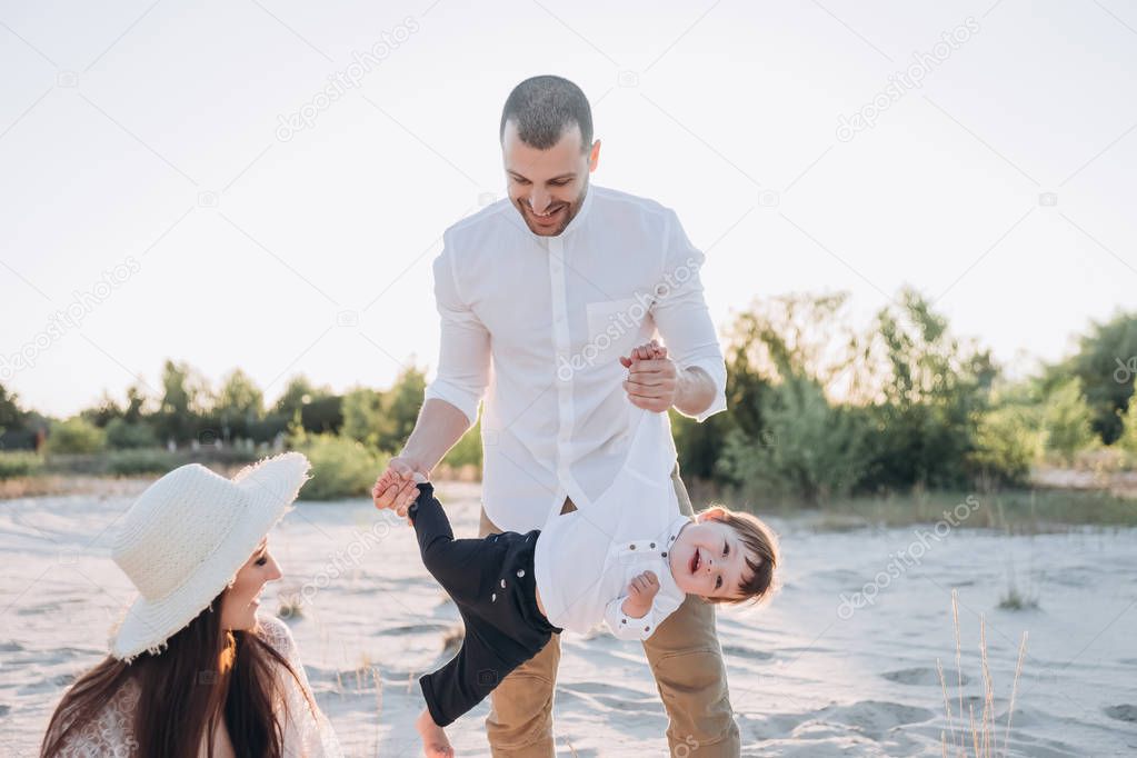 beautiful happy parents playing with little baby on beach