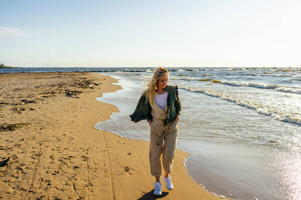 young smiling woman in stylish clothing on seashore on summer day