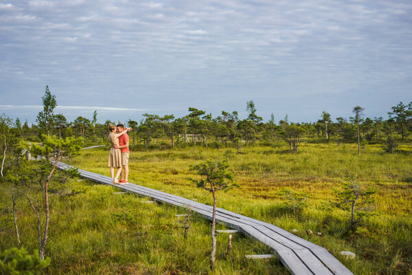 couple in love hugging on wooden bridge with blue sky and green plants on background