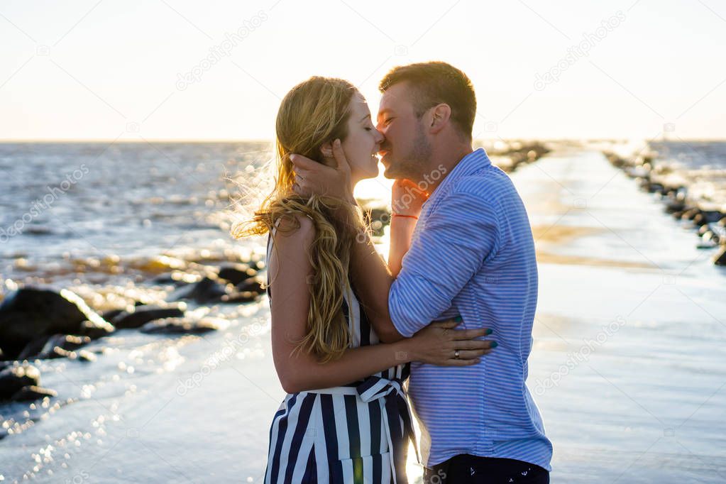 beautiful couple in love hugging and kissing on seashore during sunset in Riga, Latvia